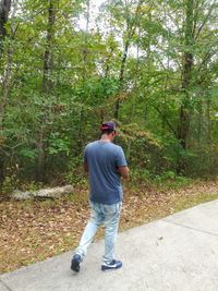 Rear view of man walking on footpath in forest