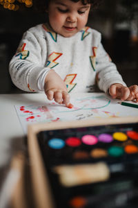 Girl painting over paper on table