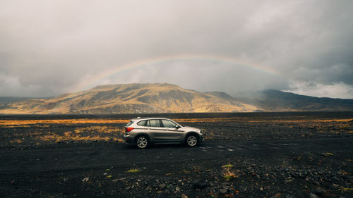 Car on road against rainbow in mountains
