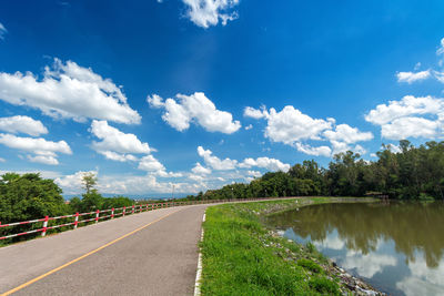 Road amidst trees against blue sky