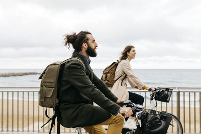 Couple riding e-bikes on beach promenade