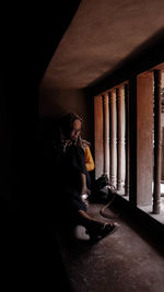 Woman looking through window in building