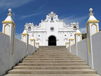 Low angle view of cross amidst buildings against sky