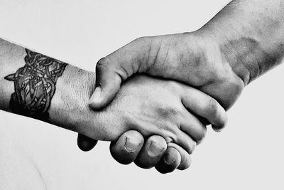 Cropped image of people shaking hands against white background