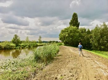 Rear view of person walking on land against sky