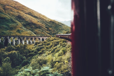 Scenic view of mountains against sky seen through train window