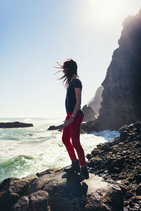 Rear view of woman standing on rock at beach