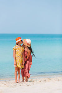 Rear view of women on beach against sky