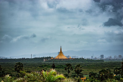 Temple on landscape against cloudy sky