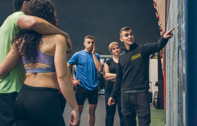 Instructor explaining over blackboard to athletes in gym