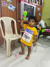 Full length of cute girl sitting on chair at home