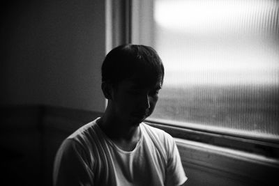 Portrait of boy looking through window at home