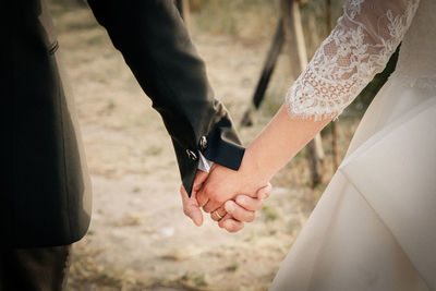 Midsection of newlywed couple holding hands