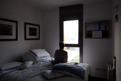 Rear view of man relaxing on bed at home