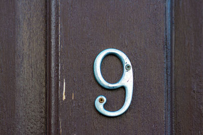 House number 9 on a black wooden front door 