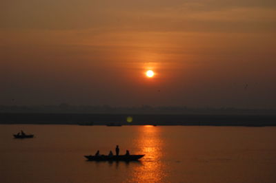 Silhouette boat in sea against sky during sunset