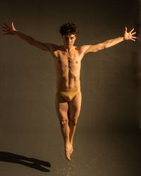 Full length of shirtless man against gray background