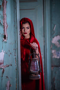 Portrait of young woman standing against red wall