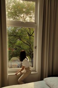 Woman looking through window at home