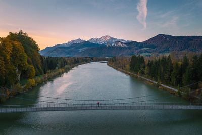 Aerial view of man standing on bridge over salzach river at sunset, salzburg, austria.