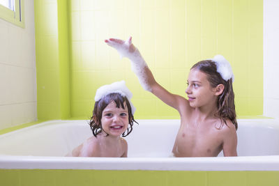 Siblings taking bath in tub at bathroom