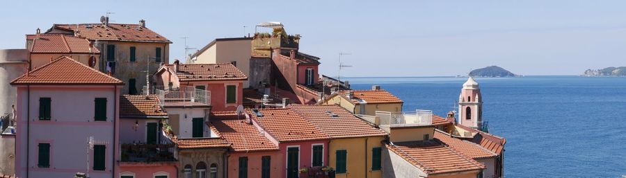 Buildings by sea against sky