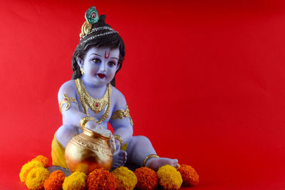 Full length of a buddha statue against red background