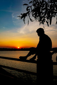 Silhouette man standing by sea against sky during sunset