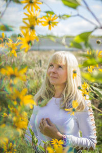 Portrait of woman with yellow flower in field