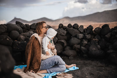 Rear view of woman sitting on rock