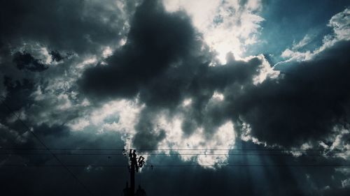 Low angle view of electricity pylon against cloudy sky