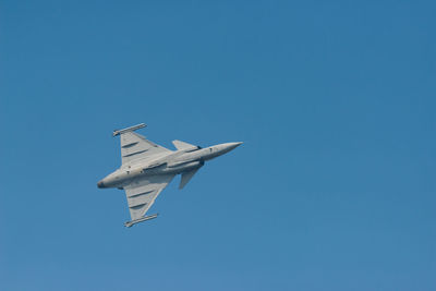 Low angle view of airplane flying against clear blue sky