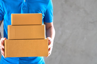 Midsection of man holding paper while standing against white wall