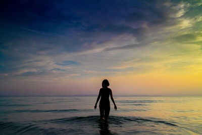 Silhouette man on beach against sky during sunset