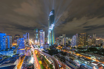 Illuminated modern buildings in city against sky at night