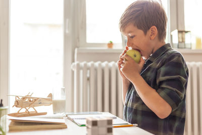 Elementary student eating an apple while learning at home during coronavirus pandemic.