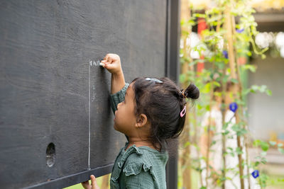 Portrait of cute girl writing alphabet on blackboard