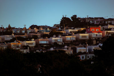 Buildings in city against clear blue sky