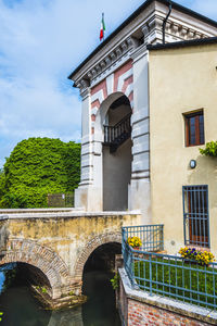 Low angle view of arch bridge and building against sky