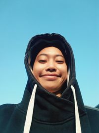 Portrait of smiling young woman against clear blue sky