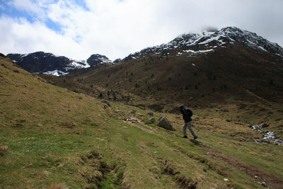 Rear view of person walking on snowcapped mountain against sky