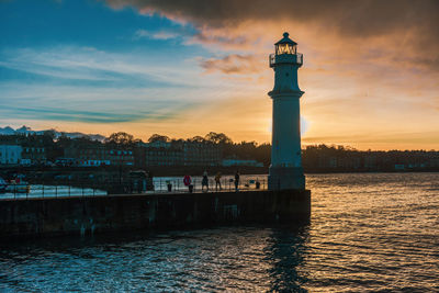 View of lighthouse in city at sunset