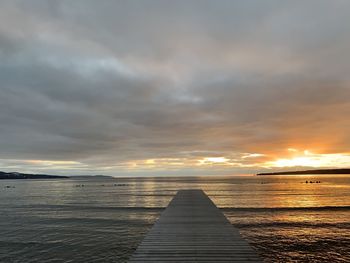 Pier over sea against sky during sunset