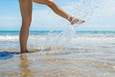 Low section of woman splashing water