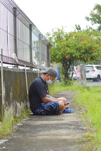 Side view of young man sitting on grass