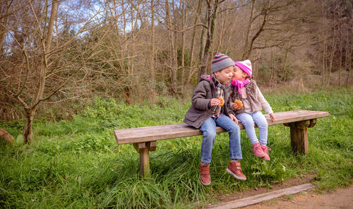 Full length of woman sitting on bench against trees