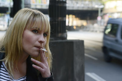 Close-up of young woman smoking cigarette by road