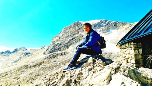 Full length of young woman standing on mountain against sky