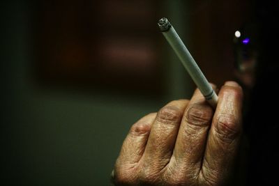 Close-up of cropped hand holding cigarette