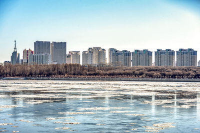 Buildings by sea against clear sky